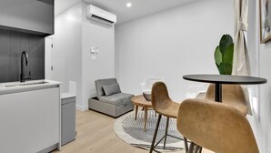 A modern kitchen with a built-in sink and a grey sofa. - Lovely, spacious & stylish studio, sleeps 3 (Montréal)