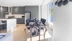 Une cuisine moderne avec des meubles gris, un îlot central et un coin repas comprenant une table et des chaises.