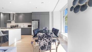 A modern kitchen with grey cabinets, a central island, and a dining area with a table and chairs.