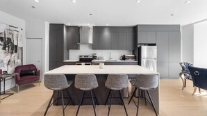 Une cuisine moderne dotée d’un îlot central, de meubles gris et d’appareils électroménagers en acier inoxydable.