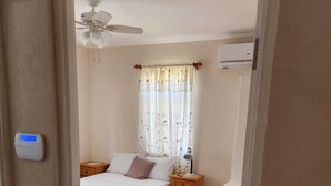Une chambre à coucher avec un lit, une table de chevet, une lampe et un ventilateur de plafond.