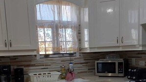 Une cuisine compacte avec des meubles blancs, un four à micro-ondes, un grille-pain, un lave-vaisselle et une cuisinière.