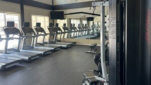 A gym with treadmills, a weight bench, and a large mirror.