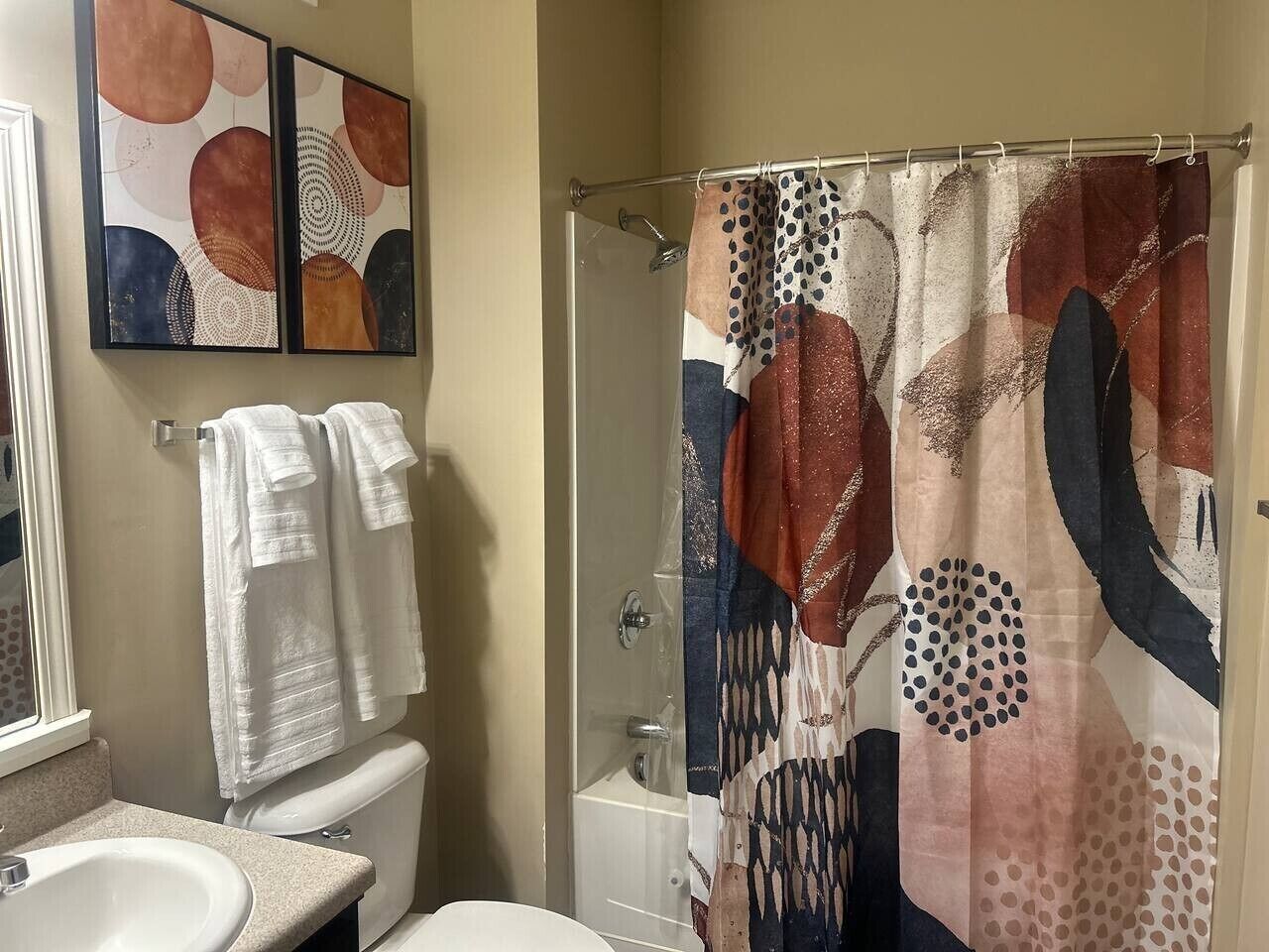 A bathroom with a shower curtain, a toilet, and a sink.