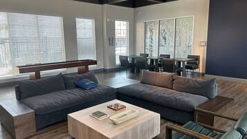 Ein modernes Wohnzimmer mit einem Ecksofa, einem Couchtisch und einem Essbereich mit Stühlen.