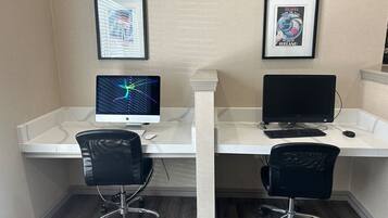 Un espacio de trabajo con dos escritorios, cada uno con un monitor de computadora, teclado y silla.