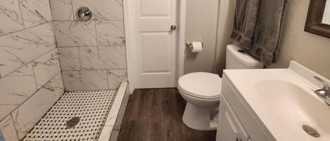 A bathroom with a shower, toilet, and sink.