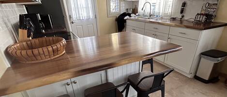 A kitchen with a wooden island, two bar stools, and a sign that reads "KITCHEN".
