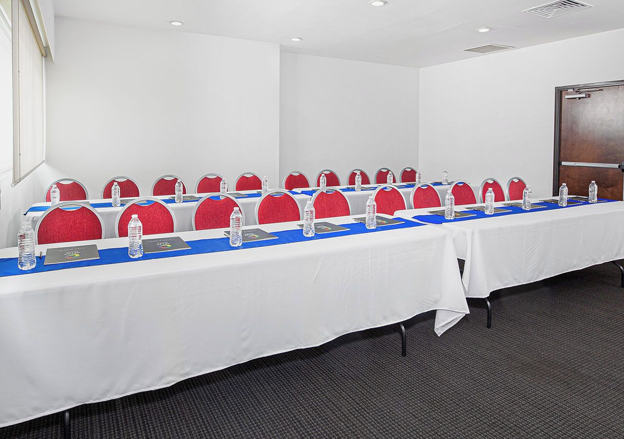 A conference room with a long table, red chairs, and water bottles.