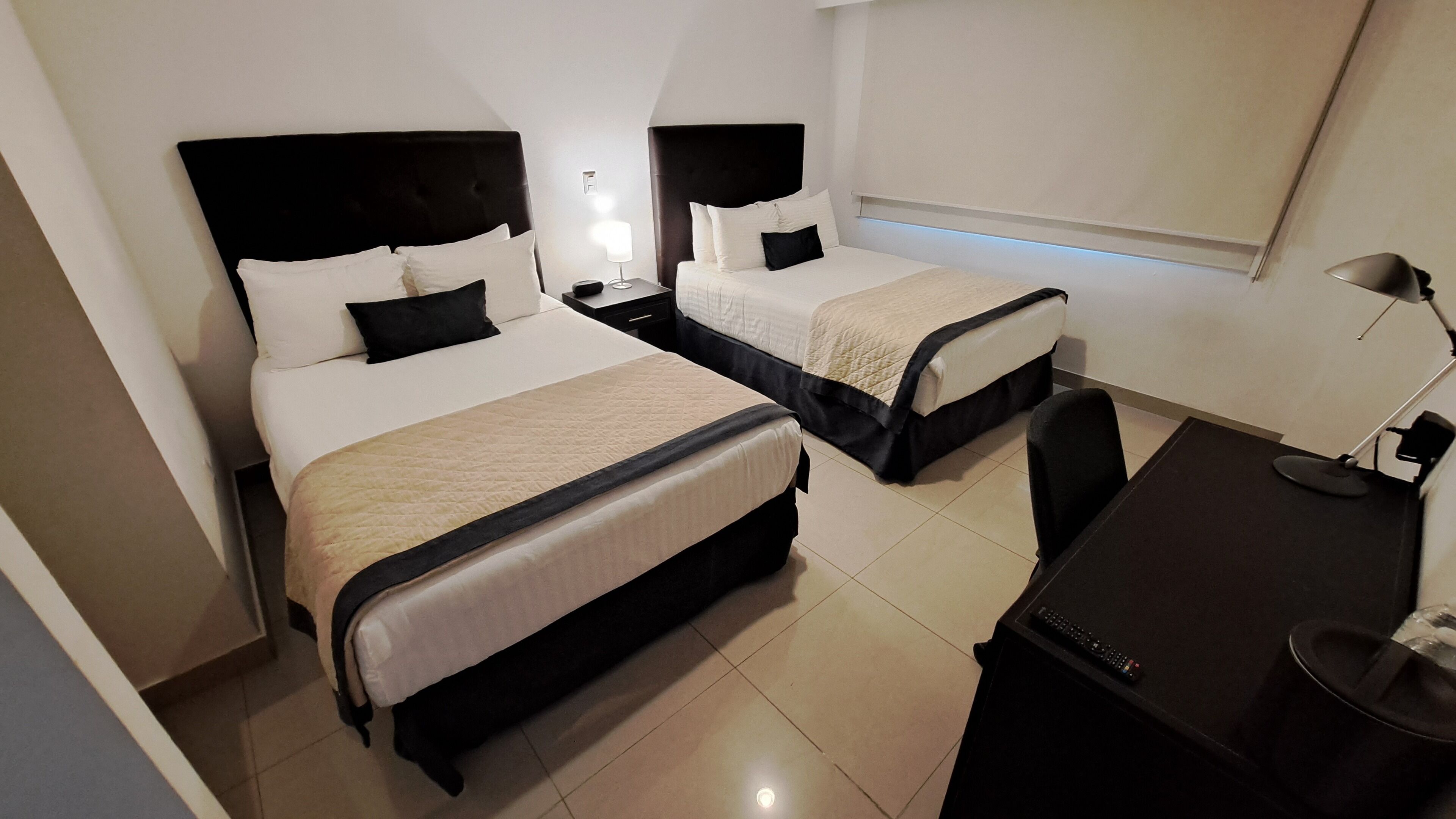 Habitación de hotel con dos camas, un escritorio y una silla.