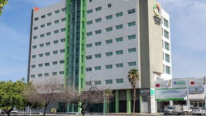 Un edificio de varios pisos con una sección vertical verde, numerosas ventanas y un letrero que indica que es un hotel.