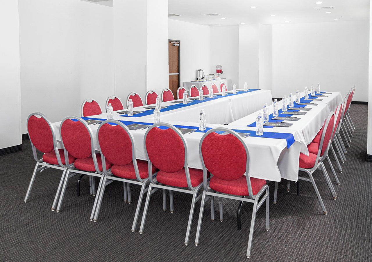 A conference room with a long table, red chairs, and water bottles.