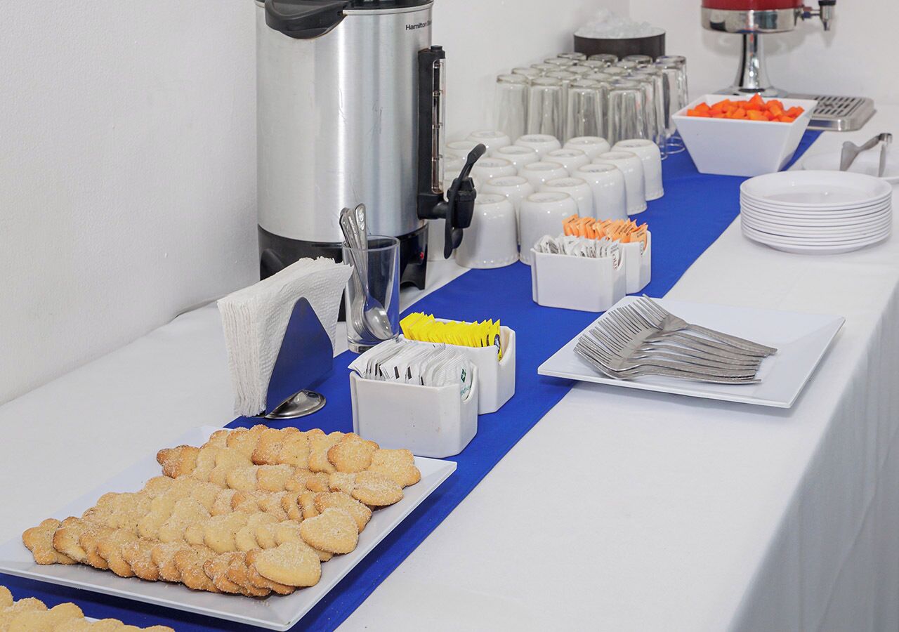 A buffet table with various food items, including cookies, a coffee station, and condiments.
