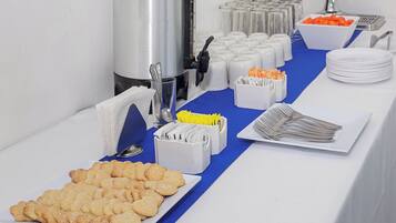 A buffet table with various food items, including cookies, a coffee station, and condiments.