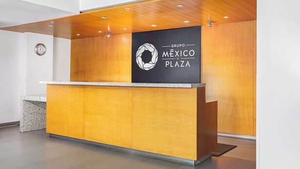 Un mostrador de recepción con detalles de madera y un cartel que dice 'Grupo Mexico Plaza'.
