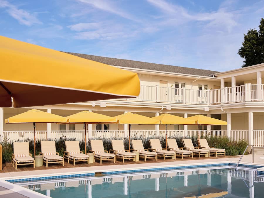 A poolside area with lounge chairs and yellow umbrellas.