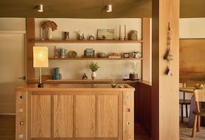 A wooden reception desk with a notepad, a vase with dried flowers, and various decorative items on shelves above. - Oyster Estate (Greenport)