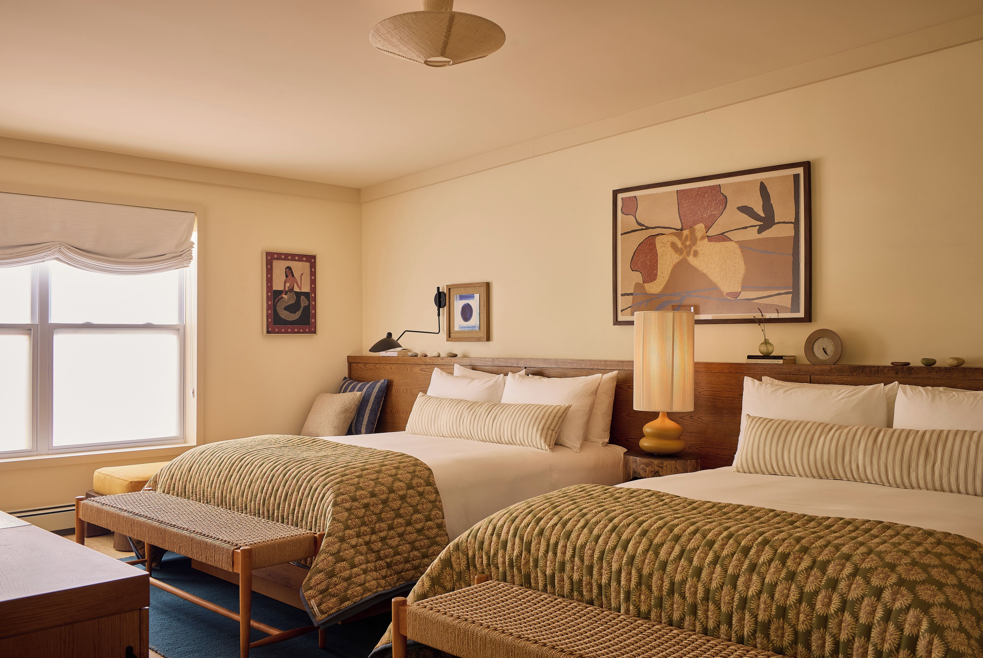 A hotel room with two beds, a desk, and a chair.
