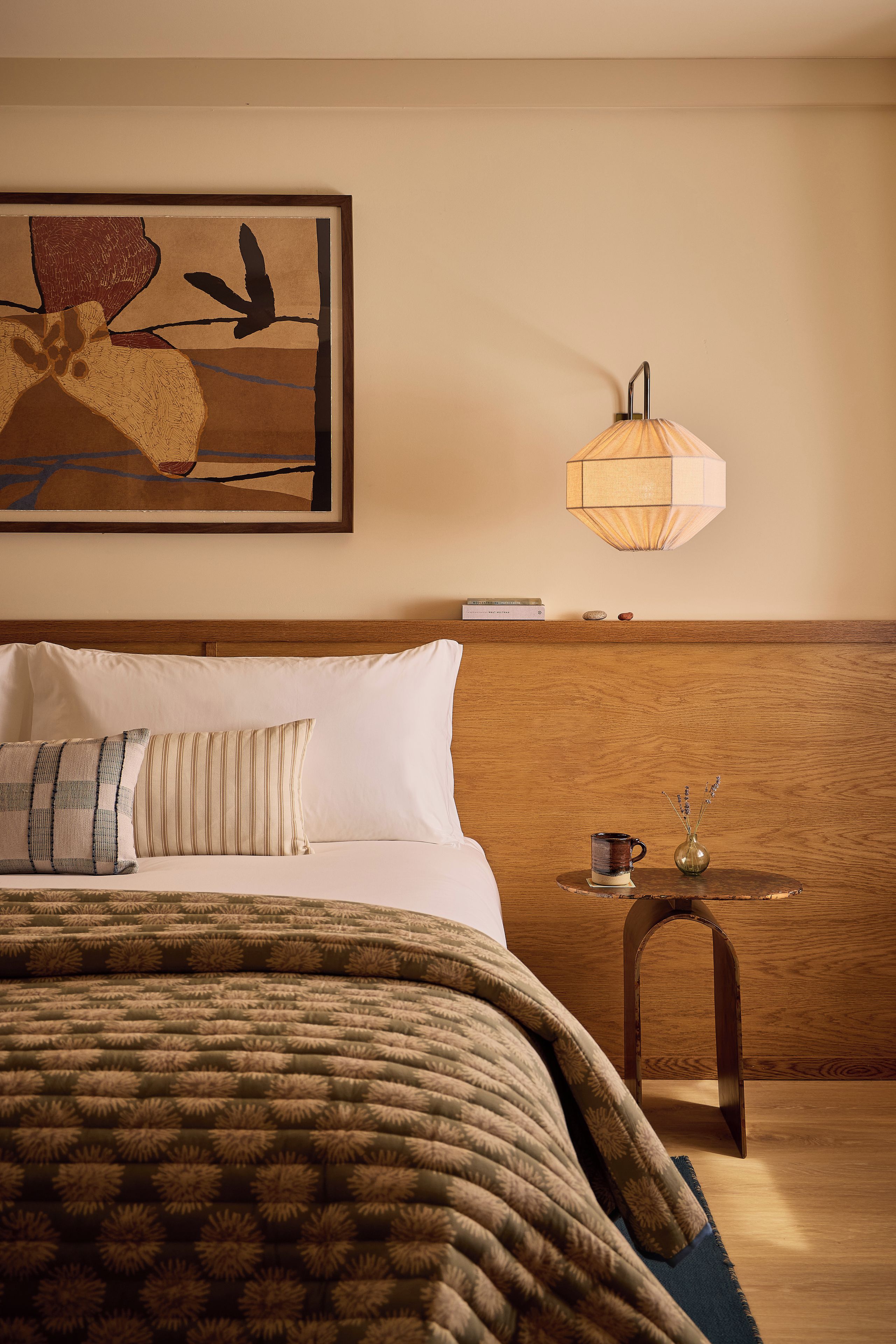 Una habitación de hotel con una cama, una mesita de noche, una lámpara y un cuadro en la pared.