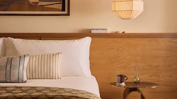 Una habitación de hotel con una cama, una mesita de noche, una lámpara y un cuadro en la pared.