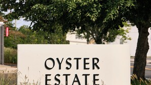 A sign for Oyster Estate with a tree in the background. - Oyster Estate (Greenport)