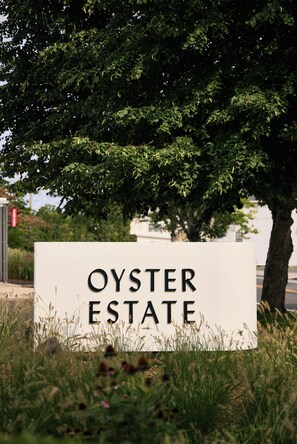Ein Schild für Oyster Estate mit einem Baum im Hintergrund.