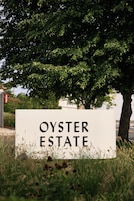 A sign for Oyster Estate with a tree in the background.