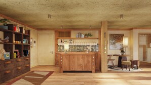 A spacious room with a wooden bar area, shelves with books and decorative items, a patterned wall, and a large window. - Oyster Estate (Greenport)