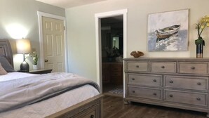 Ein Schlafzimmer mit Bett, Schminktisch und einem Bild eines Bootes an der Wand.