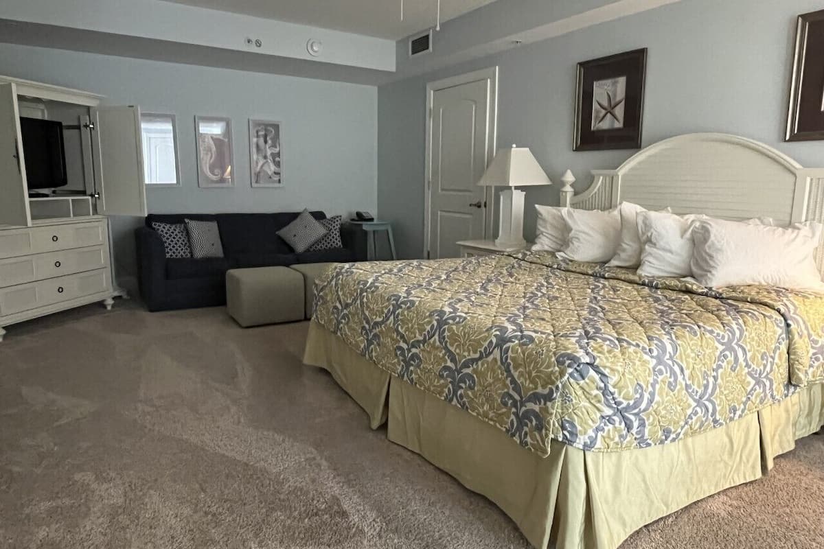 Un dormitorio con cama, cómoda, mesita de noche y sofá.