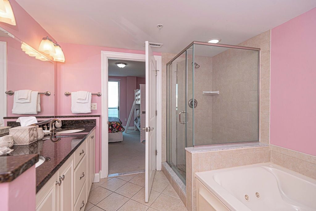 Une salle de bain dotée d’une douche à parois de verre, d’une grande baignoire et d’un meuble-lavabo avec un évier et un miroir.
