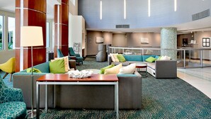 A spacious lobby with a modern design, featuring a large seating area with sofas and armchairs, a central table, and a patterned carpet. - Miramar Condominiums (Ocean City)