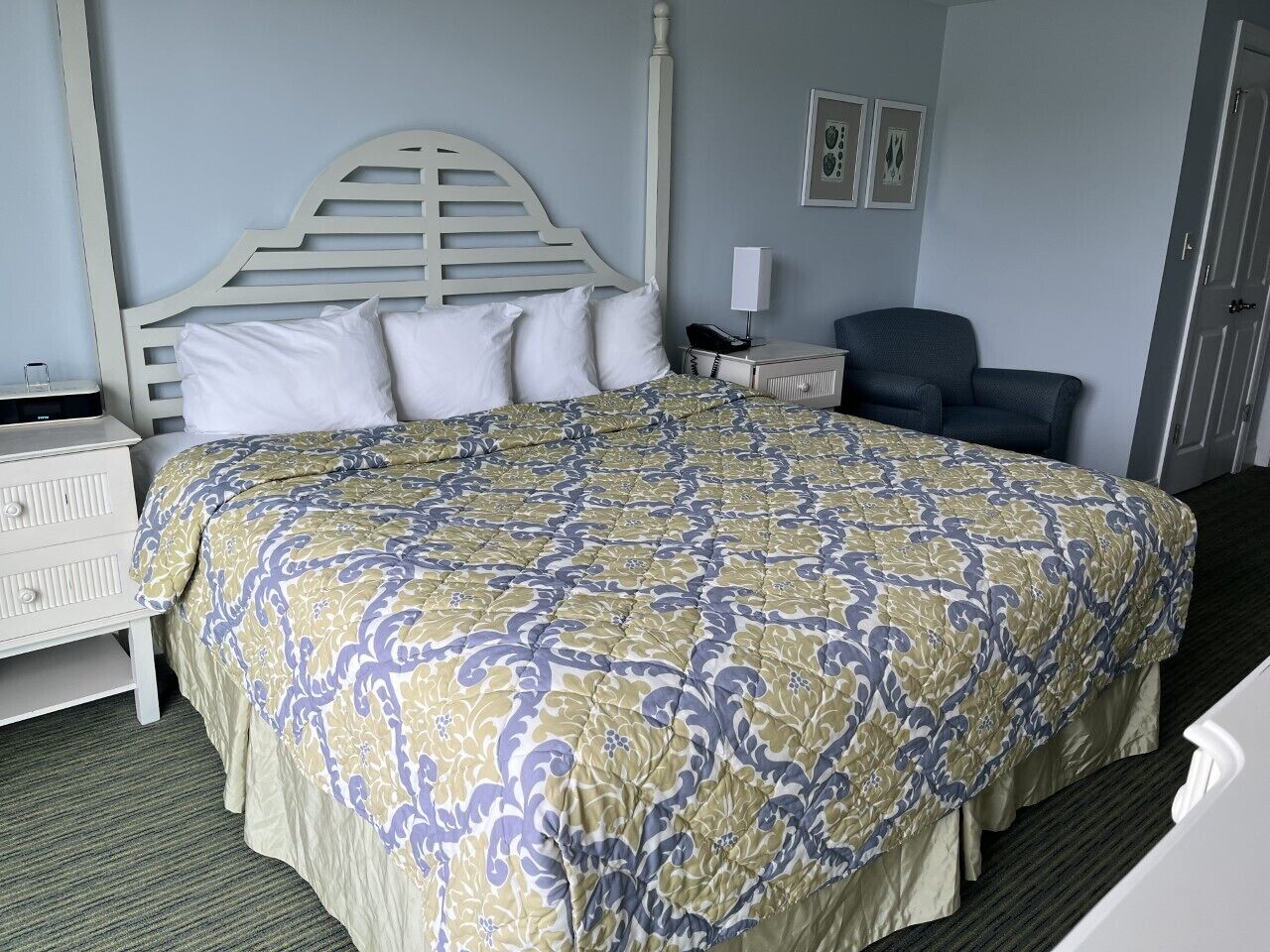 A hotel room with a large bed, a nightstand, a chair, and a desk.
