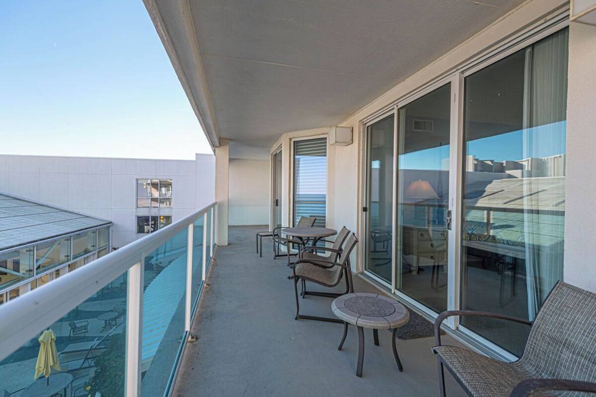 Un balcón con mobiliario exterior, ventanas amplias y vista al océano.