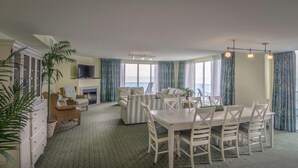A spacious room with a dining area, a fireplace, and a television. - Miramar Condominiums (Ocean City)