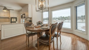 Une cuisine avec une table à manger, des chaises et un luminaire suspendu.