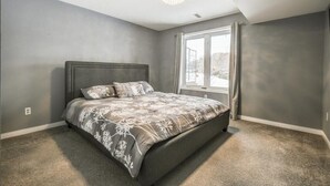 Une chambre à coucher avec un grand lit, un lustre et une fenêtre avec des rideaux.