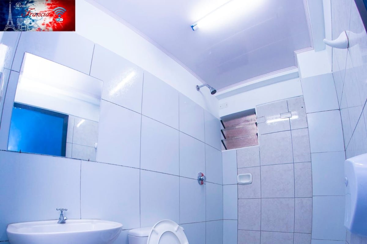 A bathroom with a white sink, toilet, and shower area.