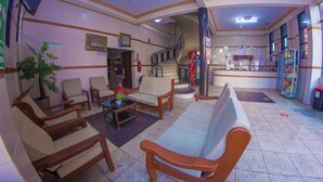 A lobby with seating, a Coca-Cola refrigerator, a staircase, and a reception desk. - residencial francia - Hostel (Santa Cruz)