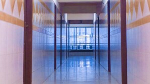 A long, narrow hallway with tiled walls and a tiled floor, leading to a bright area with windows. - residencial francia - Hostel (Santa Cruz)