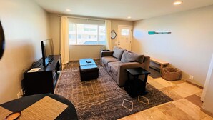 A compact living space with a sofa, a small table, a TV, and a window with curtains.