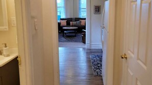 A hallway leading to a living area with a sofa, coffee table, and patterned rug. - Renovated & Fully Equipped 2 BR Apt - Hidden Gem! (St louis)