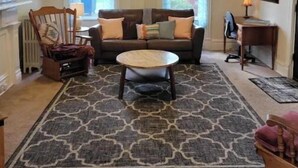 A living room with a sofa, a coffee table, a chair, a floor lamp, and a ceiling fan. - Renovated & Fully Equipped 2 BR Apt - Hidden Gem! (St louis)