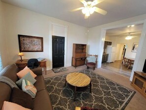 A living room with a brown sofa, a round coffee table, and a ceiling fan.