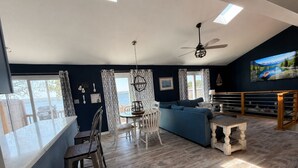 Un espacio moderno para vivir con comedor, sofá, televisión y vistas al exterior.