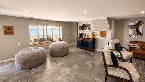 Amplia sala de estar con un ventanal grande con vista a un cuerpo de agua, un mueble de madera y un sofá de cuero.