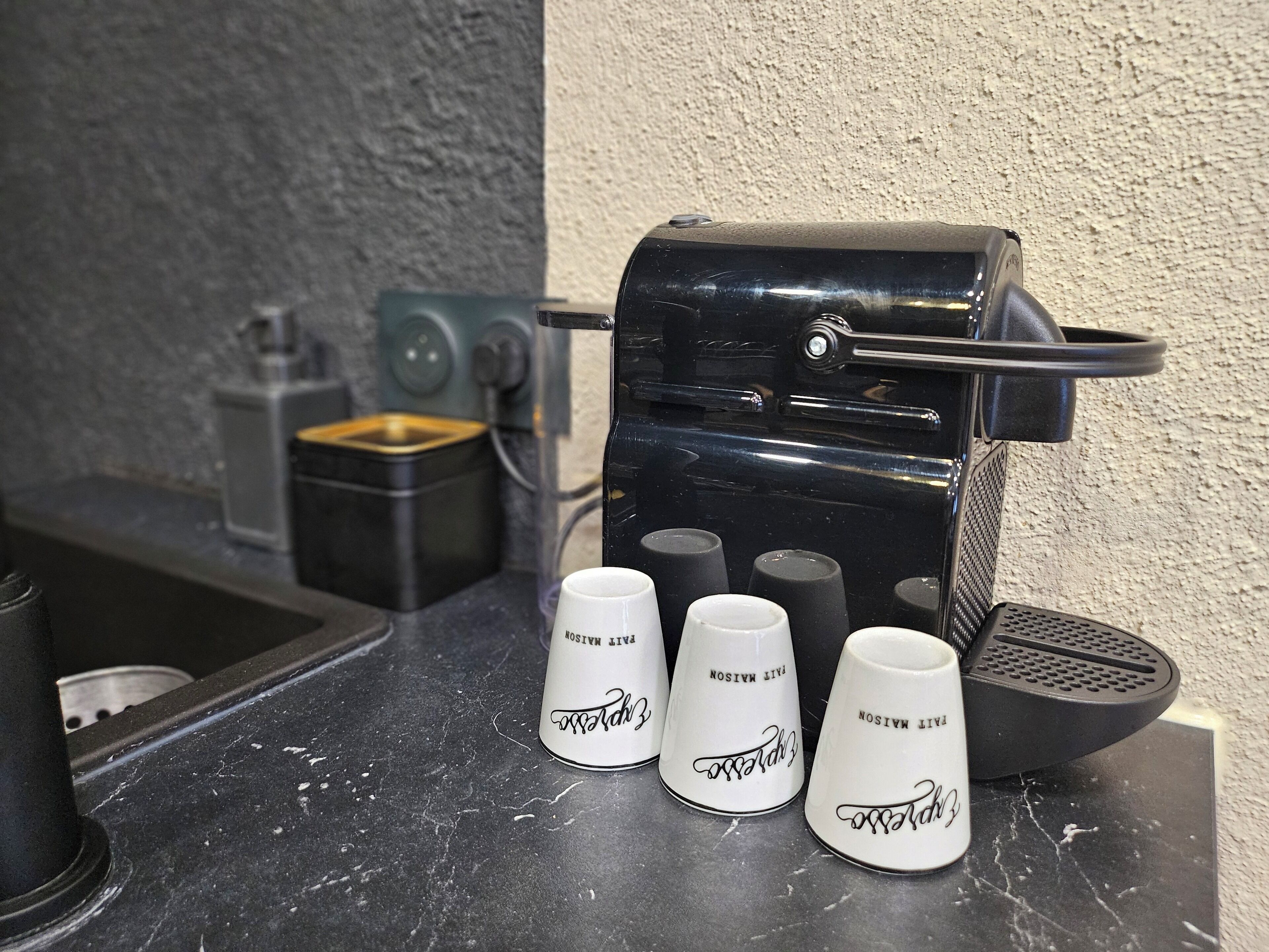 A coffee machine with three white cups on a countertop.