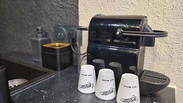 A coffee machine with three white cups on a countertop.