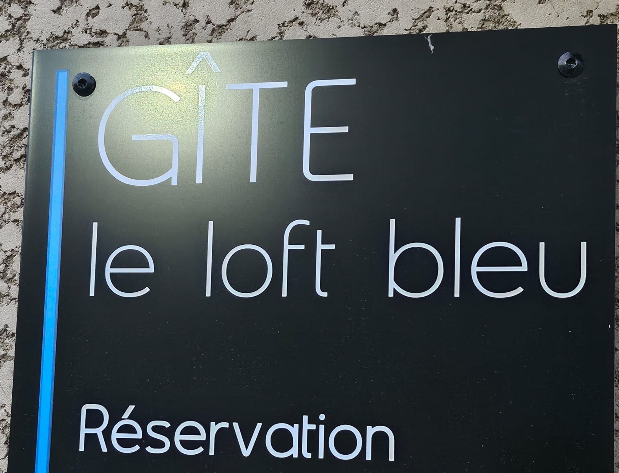 Ein Schild mit dem Text 'GITE le loft bleu' und 'Reservierung', das auf einen Bereich für Buchungen hinweist.