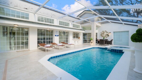 A modern indoor swimming pool with clear blue water, surrounded by lounge chairs and a sunbed. - Luxury Villa Sunrise • Star Wars Themed • Private Pool Spa (Kissimmee)
